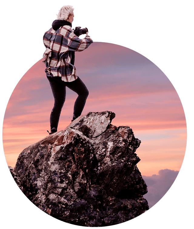 Lady taking a picture with a camera on top of a rock